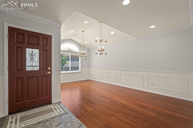 206 Luxury Ln, Colorado Springs, CO 80921 - foyer entrance featuring lofted ceiling, a chandelier, crown molding, wainscoting, and wood finished floors