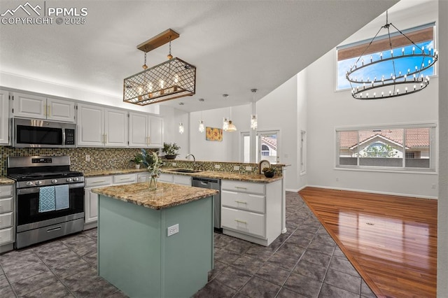 206 Luxury Ln, Colorado Springs, CO 80921 - kitchen with appliances with stainless steel finishes, a peninsula, a center island, tasteful backsplash, and a chandelier