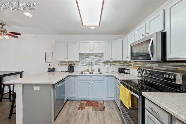 1749 Victorian Pt, Colorado Springs, CO 80905 - kitchen featuring appliances with stainless steel finishes, a peninsula, light wood-style flooring, a kitchen breakfast bar, and decorative backsplash