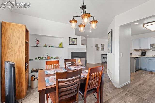 1749 Victorian Pt, Colorado Springs, CO 80905 - dining space featuring light wood-type flooring, a tiled fireplace, and a chandelier