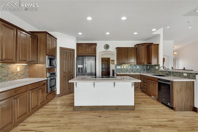11354 Mckissick Rd, Peyton, CO 80831 - kitchen with appliances with stainless steel finishes, a kitchen breakfast bar, a center island, light wood finished floors, and decorative backsplash
