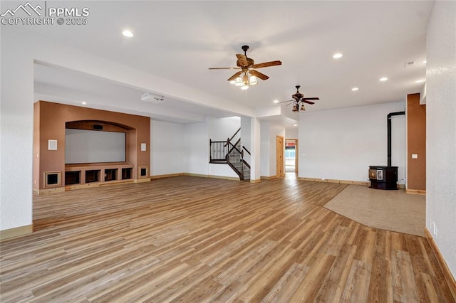 11354 Mckissick Rd, Peyton, CO 80831 - unfurnished living room with a wood stove, light wood finished floors, stairway, ceiling fan, and recessed lighting
