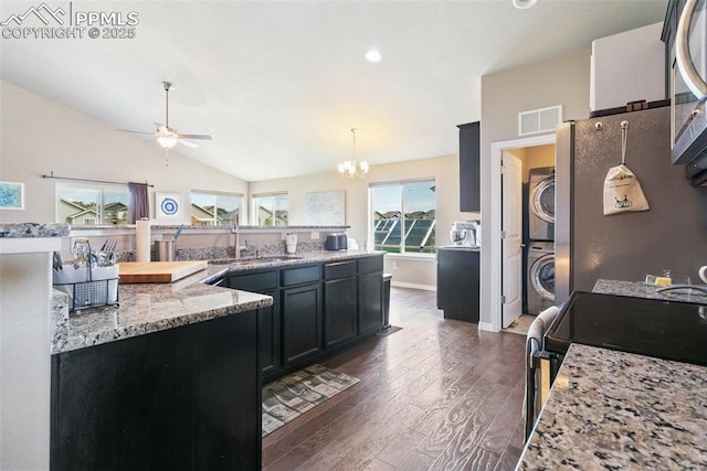 6862 Simcoe Dr, Colorado Springs, CO 80925 - kitchen with stacked washing machine and dryer, a sink, dark wood-style flooring, ceiling fan, and lofted ceiling