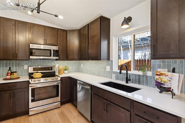 629 E Monument St, Colorado Springs, CO 80903 - kitchen with stainless steel appliances, a sink, light countertops, dark brown cabinetry, and vaulted ceiling