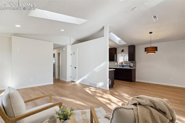 629 E Monument St, Colorado Springs, CO 80903 - living room with a skylight, light wood finished floors, vaulted ceiling, baseboards, and recessed lighting