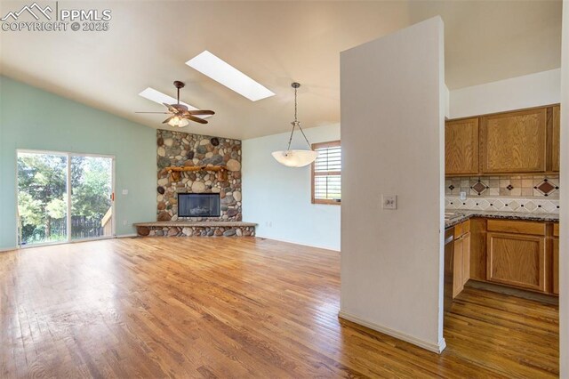 55 Misty Creek Dr, Monument, CO 80132 - unfurnished living room featuring a skylight, wood finished floors, ceiling fan, a fireplace, and high vaulted ceiling