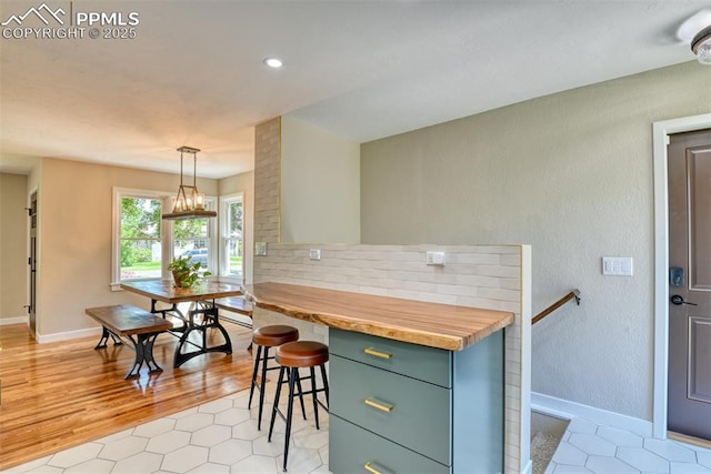 1445 N Foote Ave, Colorado Springs, CO 80909 - kitchen with a chandelier, light tile patterned flooring, butcher block countertops, recessed lighting, and a kitchen breakfast bar