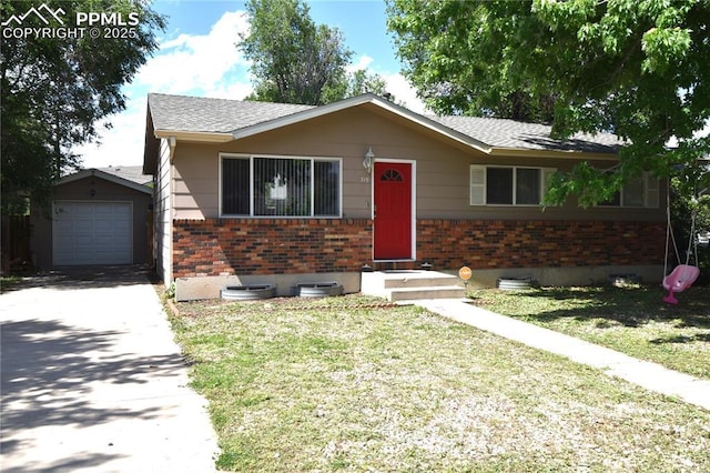 719 Lansing Dr, Colorado Springs, CO 80909 - view of front facade with brick siding, concrete driveway, a front lawn, an outbuilding, and a shingled roof