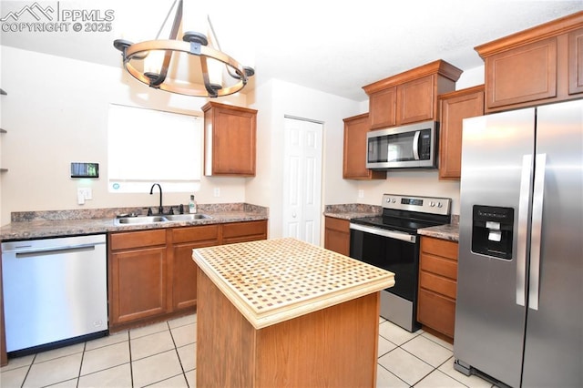 719 Lansing Dr, Colorado Springs, CO 80909 - kitchen with stainless steel appliances, a chandelier, light tile patterned floors, a center island, and brown cabinets