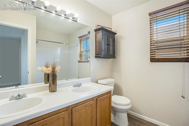 4585 W Jet Wing Cir, Colorado Springs, CO 80916 - bathroom with toilet, wood finished floors, double vanity, a shower, and baseboards