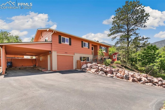 443 E Fountain Pl, Manitou Springs, CO 80829 - view of front facade featuring asphalt driveway, brick siding, an attached garage, and an attached carport
