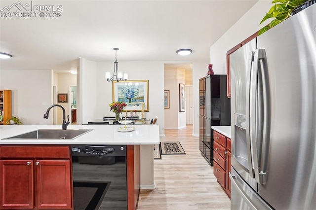 7845 Morning Dew Rd, Colorado Springs, CO 80908 - kitchen with stainless steel fridge with ice dispenser, dishwasher, reddish brown cabinets, a chandelier, and light wood-style floors