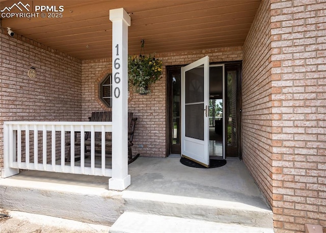 1660 Old Antlers Way, Monument, CO 80132 - view of exterior entry featuring brick siding, a porch, and a surveillance system