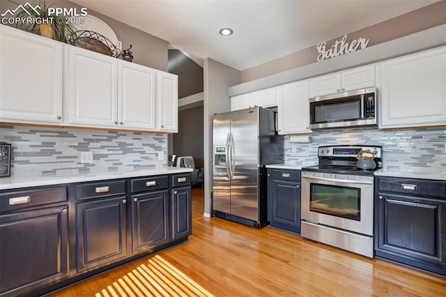 6055 Fescue Dr, Colorado Springs, CO 80923 - kitchen with appliances with stainless steel finishes, white cabinetry, light countertops, light wood-style floors, and tasteful backsplash