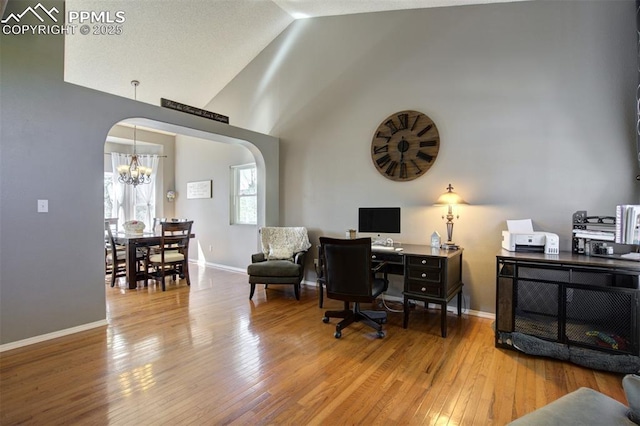 6055 Fescue Dr, Colorado Springs, CO 80923 - home office featuring arched walkways, a chandelier, wood finished floors, and high vaulted ceiling