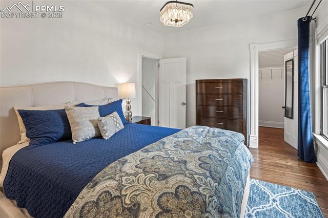 1607 W Pikes Peak Ave, Colorado Springs, CO 80904 - bedroom with wood finished floors, a walk in closet, and a chandelier