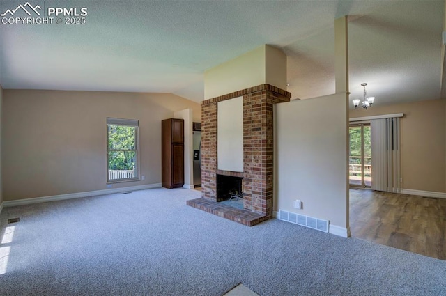 2928 Nevermind Ln, Colorado Springs, CO 80917 - unfurnished living room featuring carpet, vaulted ceiling, a chandelier, a fireplace, and a textured ceiling