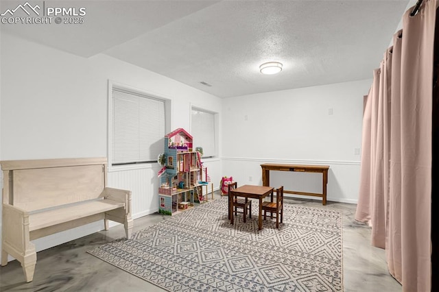 55 Woodbridge Dr, Colorado Springs, CO 80906 - game room with a textured ceiling, concrete flooring, and wainscoting