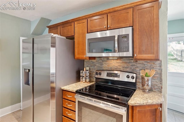 2144 Glenn St, Colorado Springs, CO 80904 - kitchen with stainless steel appliances, brown cabinetry, light tile patterned floors, decorative backsplash, and light stone counters