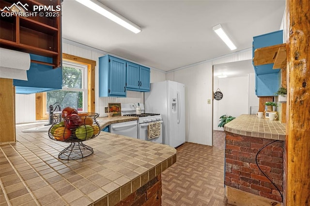 17155 Sagecreek Rd, Peyton, CO 80831 - kitchen featuring blue cabinetry, white appliances, tile countertops, and wooden walls
