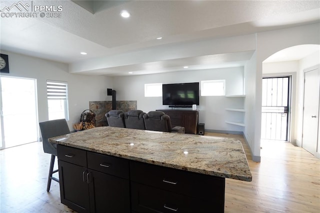 1407 Manitou Blvd, Colorado Springs, CO 80904 - kitchen featuring a wood stove, dark cabinets, light wood-style flooring, recessed lighting, and a breakfast bar