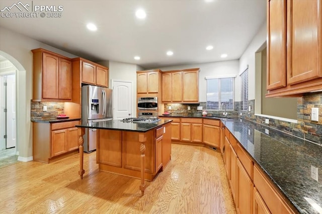 13080 Mt Harvard Dr, Peyton, CO 80831 - kitchen featuring appliances with stainless steel finishes, tasteful backsplash, arched walkways, light wood-type flooring, and recessed lighting