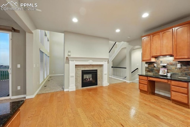 13080 Mt Harvard Dr, Peyton, CO 80831 - kitchen featuring light wood finished floors, backsplash, recessed lighting, dark stone counters, and a tiled fireplace