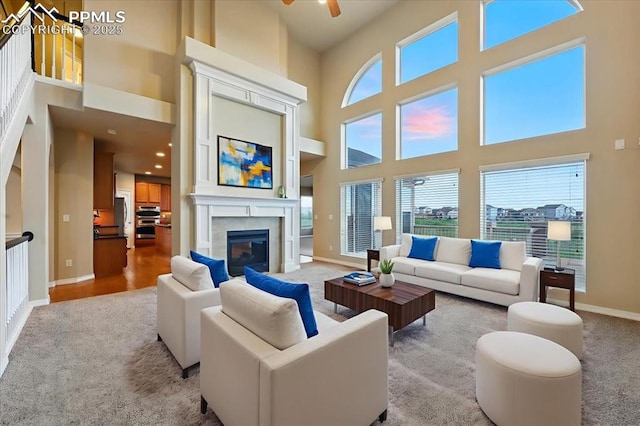 13080 Mt Harvard Dr, Peyton, CO 80831 - living area featuring a towering ceiling, plenty of natural light, light colored carpet, ceiling fan, and a glass covered fireplace