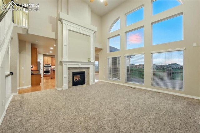 13080 Mt Harvard Dr, Peyton, CO 80831 - unfurnished living room featuring a towering ceiling, light colored carpet, and a tiled fireplace