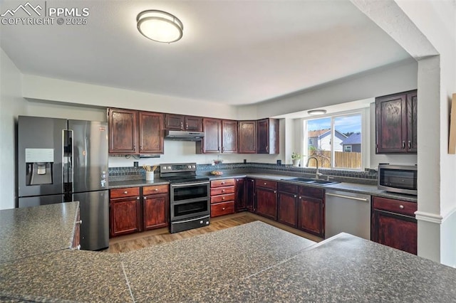 2852 Front Royal Dr, Colorado Springs, CO 80919 - kitchen featuring appliances with stainless steel finishes, dark countertops, under cabinet range hood, light wood-style floors, and dark brown cabinets