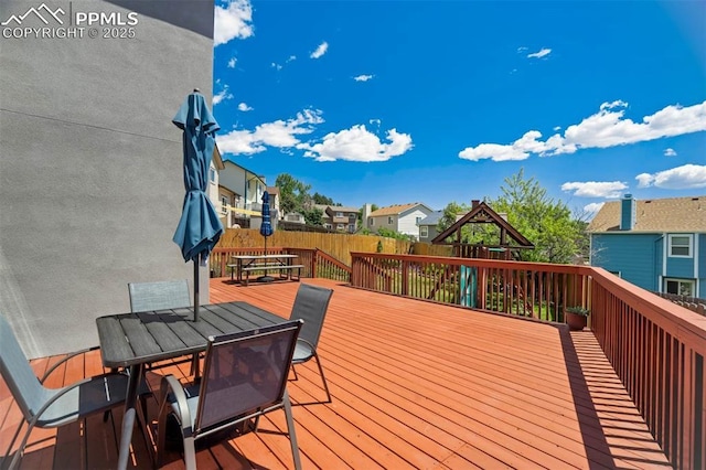 2852 Front Royal Dr, Colorado Springs, CO 80919 - wooden deck featuring outdoor dining space, a playground, a fenced backyard, and a residential view