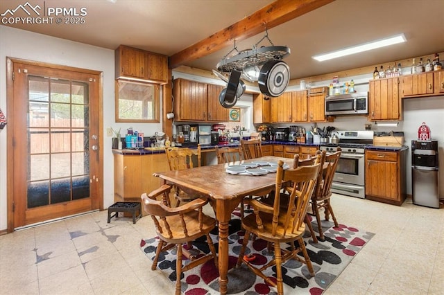 125 1st St, Saguache, CO 81149 - kitchen with stainless steel appliances, brown cabinetry, light flooring, and beamed ceiling