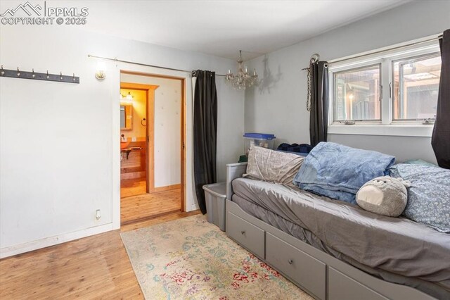 125 1st St, Saguache, CO 81149 - bedroom with wood finished floors, a chandelier, and connected bathroom