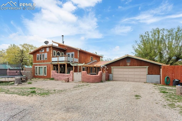 125 1st St, Saguache, CO 81149 - view of front facade with a trampoline, a garage, gravel driveway, and a balcony