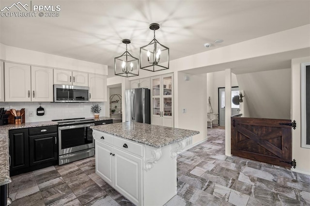 2570 Wimbleton Ct, Colorado Springs, CO 80920 - kitchen with appliances with stainless steel finishes, white cabinets, light stone counters, and a chandelier