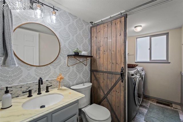 2570 Wimbleton Ct, Colorado Springs, CO 80920 - bathroom featuring separate washer and dryer, vanity, decorative backsplash, and stone finish floors