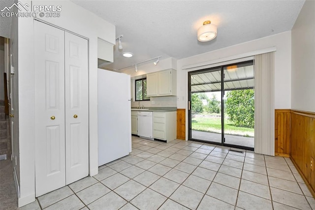 4059 Cooke Ln, Colorado Springs, CO 80911 - kitchen with white appliances, wood walls, a textured ceiling, wainscoting, and track lighting