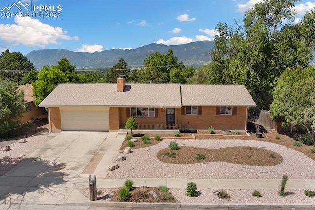 1411 Acacia Dr, Colorado Springs, CO 80907 - ranch-style house with concrete driveway, brick siding, a garage, and a chimney