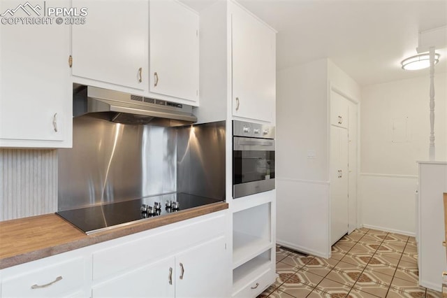 1411 Acacia Dr, Colorado Springs, CO 80907 - kitchen with under cabinet range hood, stainless steel oven, black electric cooktop, and white cabinets