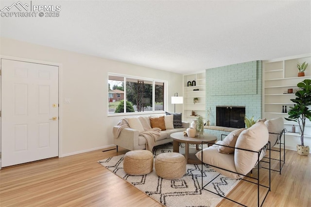 1411 Acacia Dr, Colorado Springs, CO 80907 - living area featuring light wood finished floors, a textured ceiling, a fireplace, and built in shelves