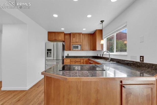 5105 Stellar Dr, Colorado Springs, CO 80923 - kitchen with appliances with stainless steel finishes, tile countertops, brown cabinets, a peninsula, and light wood-style floors