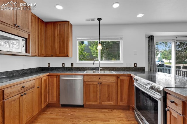 5105 Stellar Dr, Colorado Springs, CO 80923 - kitchen with stainless steel appliances, dark countertops, light wood finished floors, brown cabinetry, and recessed lighting