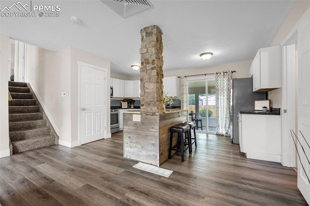 519 Crest St, Fountain, CO 80817 - kitchen featuring white cabinetry, a kitchen island, a breakfast bar area, dark wood-type flooring, and stainless steel range