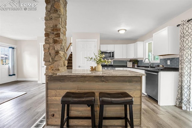 519 Crest St, Fountain, CO 80817 - kitchen featuring stainless steel appliances, a breakfast bar, light wood finished floors, and plenty of natural light