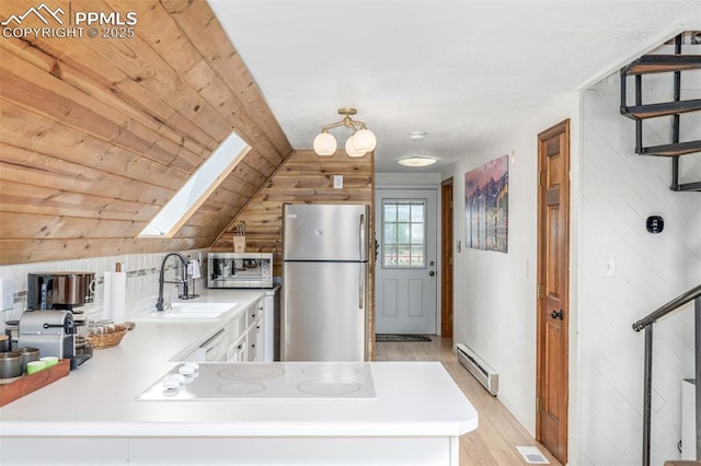 860 Golden Cycle Cir, Cripple Creek, CO 80813 - kitchen featuring appliances with stainless steel finishes, a skylight, baseboard heating, wood walls, and light wood-style flooring
