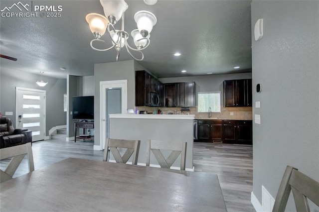2485 Falkirk Dr, Colorado Springs, CO 80910 - kitchen featuring stainless steel microwave, dark brown cabinetry, light wood finished floors, open floor plan, and baseboards