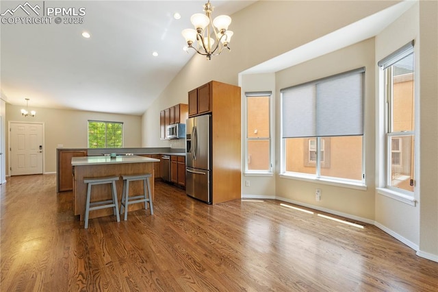 4410 Campus Bluffs Ct, Colorado Springs, CO 80918 - kitchen with a chandelier, appliances with stainless steel finishes, a kitchen island, brown cabinetry, and dark wood-style floors