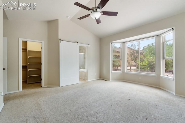 4410 Campus Bluffs Ct, Colorado Springs, CO 80918 - unfurnished bedroom with a barn door, carpet flooring, a walk in closet, lofted ceiling, and connected bathroom