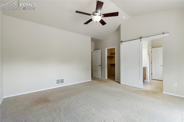 4410 Campus Bluffs Ct, Colorado Springs, CO 80918 - unfurnished bedroom with a barn door, light carpet, a walk in closet, a ceiling fan, and a closet