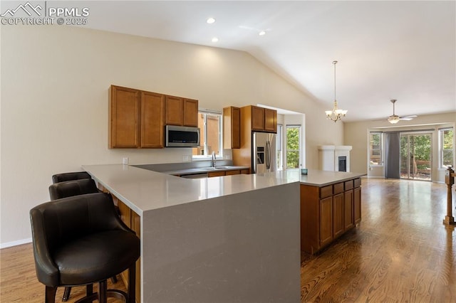 4410 Campus Bluffs Ct, Colorado Springs, CO 80918 - kitchen featuring appliances with stainless steel finishes, lofted ceiling, brown cabinets, open floor plan, and wood finished floors